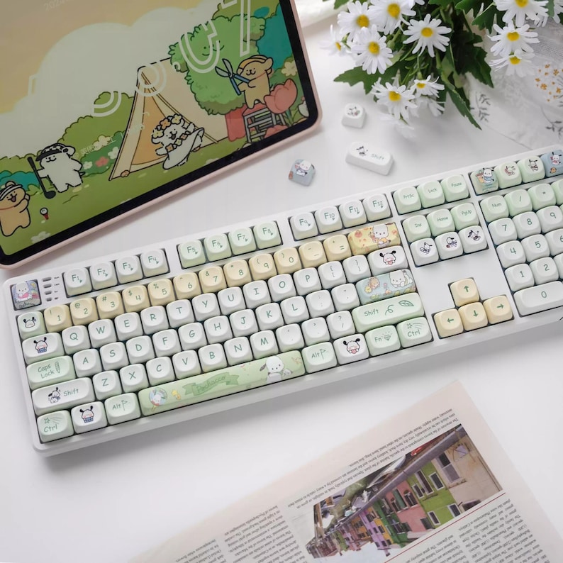May include: A white keyboard with pastel green, yellow, and pink keycaps featuring cartoon animal illustrations. The keyboard has a white frame and a white cable.