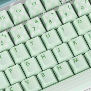 May include: A mint green keyboard with white lettering. The keys are labeled with letters, numbers, and symbols. The keyboard has a light green and white marbled design.