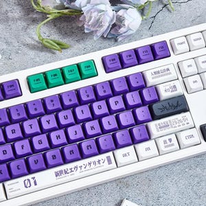 May include: A white mechanical keyboard with purple and green keycaps. The keyboard has a Japanese language layout and features a "Neon Genesis Evangelion" themed design. The keyboard has a white and purple color scheme and features a variety of keycaps with different colors and designs.