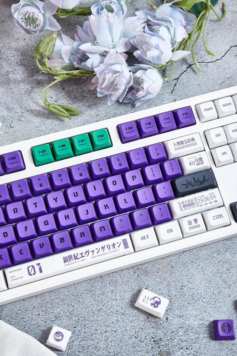 May include: A white mechanical keyboard with purple and green keycaps. The keyboard has a Japanese language layout and features a "Neon Genesis Evangelion" themed design. The keyboard has a white and purple color scheme and features a variety of keycaps with different colors and designs.