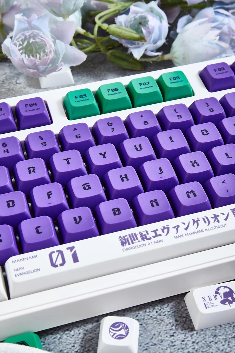May include: A white mechanical keyboard with purple and green keycaps. The keyboard has a space bar with the text "EVANGELION 01 NERV" and "MARI MAKINAMI ILLUSTRIOUS" printed on it. The keyboard also has a keycap with the text "01" printed on it.