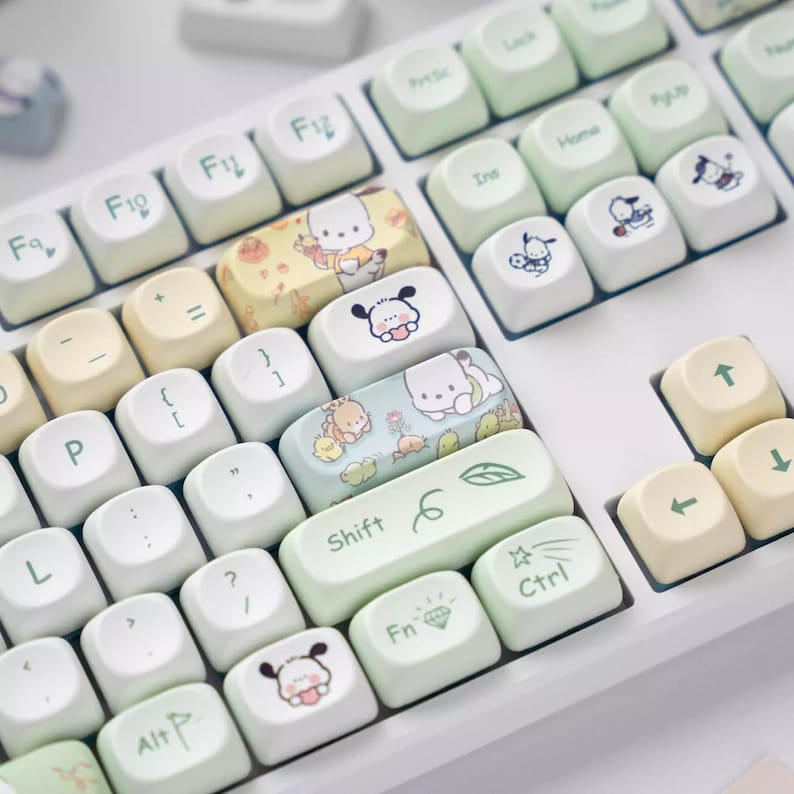 May include: A white keyboard with pastel green and yellow keycaps featuring cartoon characters. The keycaps have various designs, including a leaf, a diamond, and a star.