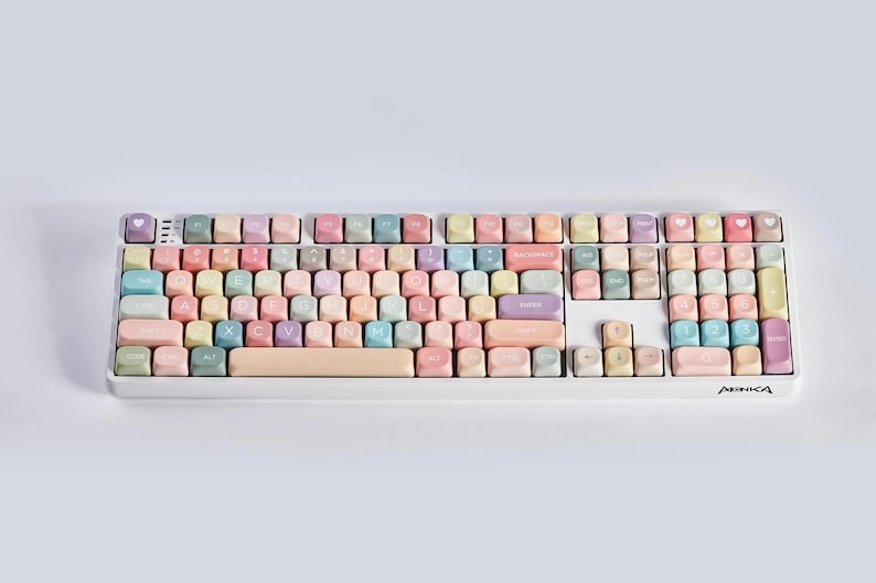May include: A white keyboard with pastel colored keys. The keys have various letters, numbers, and symbols printed on them. The keyboard has the word "ARIKA" printed on the bottom right corner.