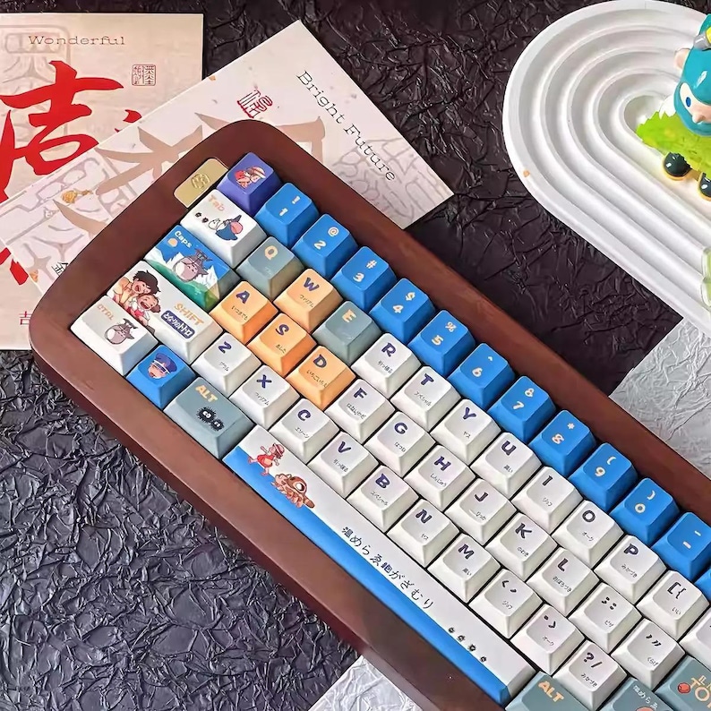 May include: A wooden keyboard with blue and white keycaps. The keyboard has a Japanese inscription that reads "堀めらゑ細がざむり".