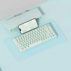May include: A light blue keyboard with white keys and a white phone on a light blue surface.