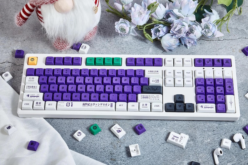 May include: A white mechanical keyboard with purple and green keycaps. The keyboard has a Japanese language layout and the text "01 暁光とエヴァンゲリオン" is printed on the bottom row of keys.