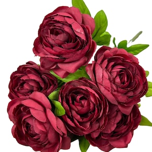 May include: A bouquet of five burgundy silk ranunculus flowers with green leaves.