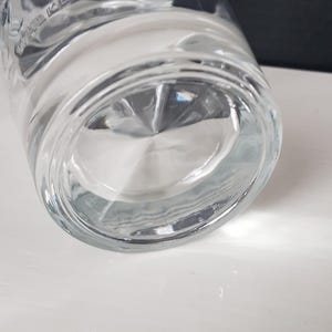 K&ouml;nnte beinhalten: Klares Trinkglas mit dickem Boden. Das Glas hat eine leichte Kr&uuml;mmung und einen abgerundeten Boden. Das Wort "WALKER" ist auf der Seite des Glases zu sehen. Das Glas steht auf einer wei&szlig;en Oberfl&auml;che.