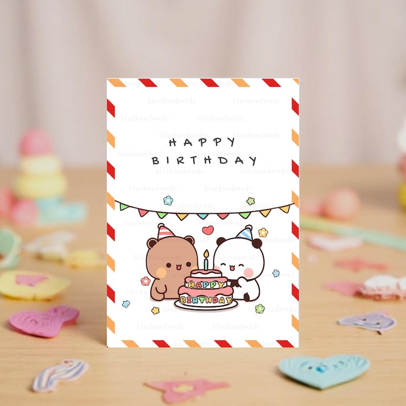 May include: A white card with red and orange stripes on the border. The card says "Happy Birthday" in black text. There are two cartoon animals, a brown bear and a black and white panda, with party hats on, standing next to a pink and yellow cake with candles. The cake says "Happy Birthday" in colorful letters.