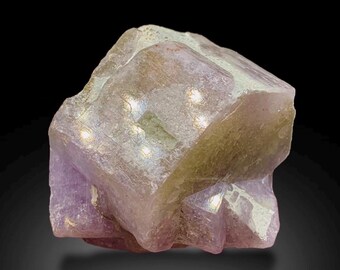 May include: A raw, uncut amethyst crystal with a light purple hue and a rough, textured surface. The gemstone has a natural, irregular shape and displays subtle variations in color, with hints of white and yellow.