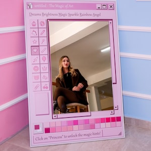 K&ouml;nnte beinhalten: Ein rosa gerahmter Spiegel mit einem Retro-Computer-Interface-Design. Der Text oben lautet "untitled - The Magic of Art" und "Dreams Brightness Magic Sparkle Rainbow Angel". Der Text unten lautet "Click on 'Princess' to unlock the magic hints!"