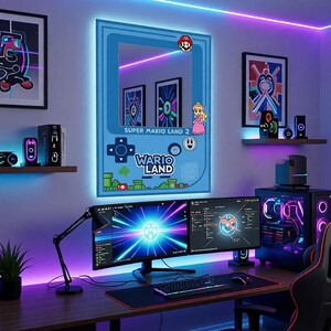May include: A gaming-themed room featuring a large blue mirror shaped like a retro handheld console, with the text "Super Mario Land 2" and "Wario Land". The room is illuminated with neon lights and includes a computer setup with dual monitors.