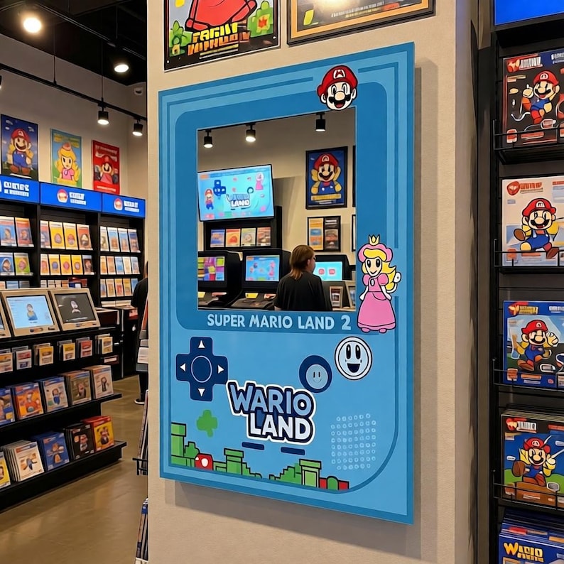 May include: A light blue wall decoration featuring the Super Mario Land 2: Wario Land game. The decoration includes images of Mario, Princess Peach, and game controller symbols. The text "SUPER MARIO LAND 2" and "WARIO LAND" are also visible.