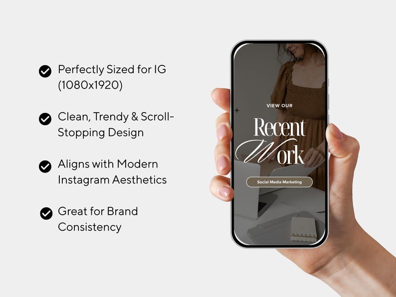 May include: A smartphone displays a social media marketing design with the text "Recent Work." The phone is held in a hand. The design includes a woman in a brown dress and the words "View Our" at the top.