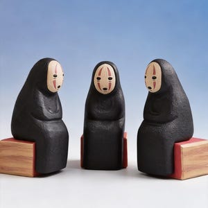 May include: Three black figures with white and red facial features, seated on wooden blocks with red accents. The figures have a rounded shape and are set against a light blue background. The figures are reminiscent of characters from a popular animated film.