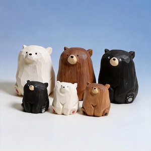 May include: Six wooden bear figurines in different sizes and colours. The bears are carved with a textured finish and feature white, brown, and black tones. Each bear has small, round eyes and a seated pose, with some showing red paw pads.