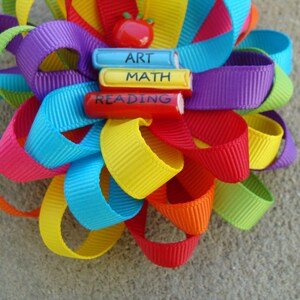 May include: A rainbow-colored ribbon bow with a red apple and three wooden blocks that say "Art", "Math", and "Reading".
