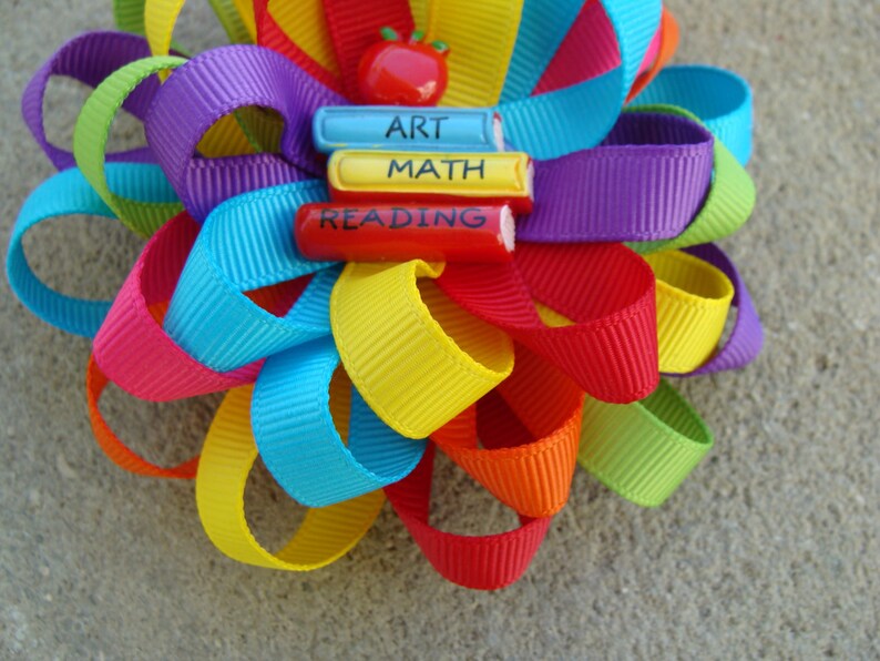 May include: A rainbow-colored ribbon bow with a red apple and three wooden blocks that say "Art", "Math", and "Reading".