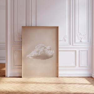 Könnte beinhalten: Ein rechteckiger Wandkunstdruck in einem hellen Holzrahmen, der eine einzelne, flauschige weiße Wolke mittig auf einem einfarbigen, gedämpften beigen Hintergrund zeigt. Das Kunstwerk ist vertikal ausgerichtet und bietet eine weiche Ästhetik.