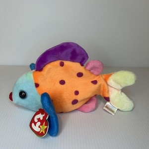 Op de afbeelding: Een kleurrijk pluche vis speelgoed met oranje, paarse, blauwe en roze accenten. De vis heeft een Ty Beanie Baby-tag bevestigd aan zijn vin.