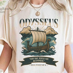 Puede incluir: Camiseta color crema con un gráfico de un barco navegando sobre olas, con la palabra "ODYSSEUS" arriba. El diseño incluye la cita "VERY BAD, WOULD NOT RECOMMEND" debajo. La camiseta es de estilo cómodo e informal.