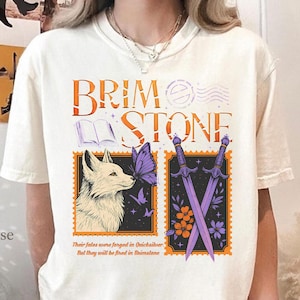 May include: Cream-colored t-shirt with the text "BRIMSTONE" in orange and purple. The shirt features a fox, butterfly, and crossed swords design. The text "Their fates were forged in Quicksilver But they will be fired in Brimstone" is printed below the design.