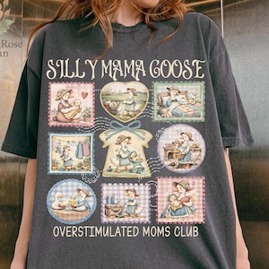 May include: Dark gray t-shirt featuring the text "SILLY MAMA GOOSE" above a collage of illustrated postage stamp designs. The stamps depict a goose character in various scenes. The phrase "OVERSTIMULATED MOMS CLUB" is printed below the stamps.