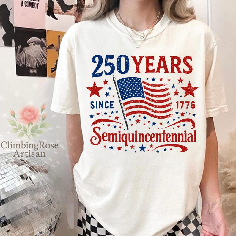 May include: Cream-colored t-shirt with a patriotic design. The design features the text "250 YEARS SINCE 1776 Semiquincentennial" in blue and red, along with an American flag and stars. The shirt is a casual style.