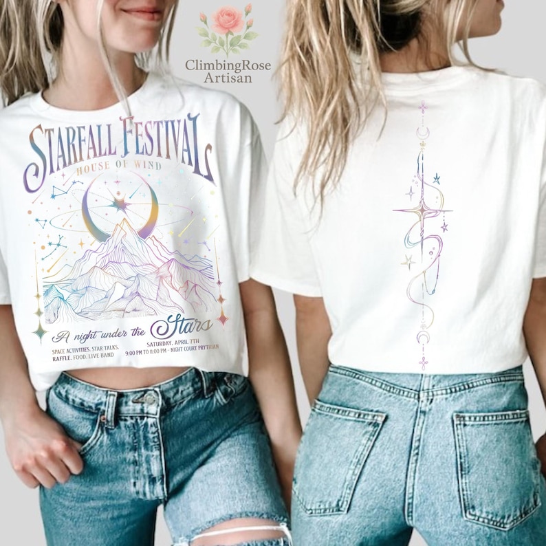 May include: White t-shirt with a colorful graphic design. The front features the text "STARFALL FESTIVAL" above a mountain scene with a crescent moon. The back has a vertical design with stars and crescent moons.