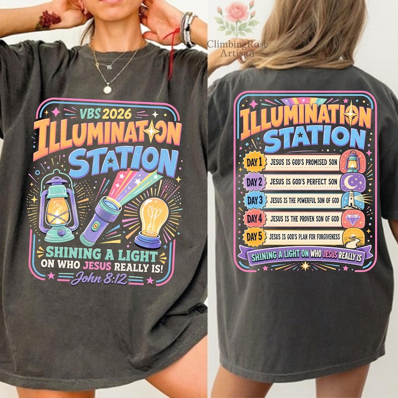 Pu&ograve; includere: T-shirt grigio scuro con un design grafico colorato. La parte anteriore presenta il testo "VBS 2026 ILLUMINATION STATION" con illustrazioni di una lanterna, una torcia e una lampadina. Il retro ha lo stesso testo e un elenco di temi giornalieri.