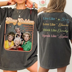 May include: Dark gray t-shirt featuring a retro design with the text "Stay Golden" and a picture of four women. The back of the shirt has text that reads "Live Like Rose, Love Like Blanche, Think Like Dorothy, Speak Like Sophia."