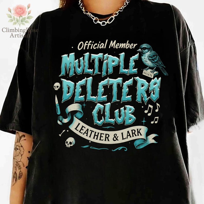 May include: Black t-shirt with a blue and white graphic design that says "Official Member Multiple Deleters Club Leather & Lark". The graphic also includes a skull, a knife, a bird, and musical notes.