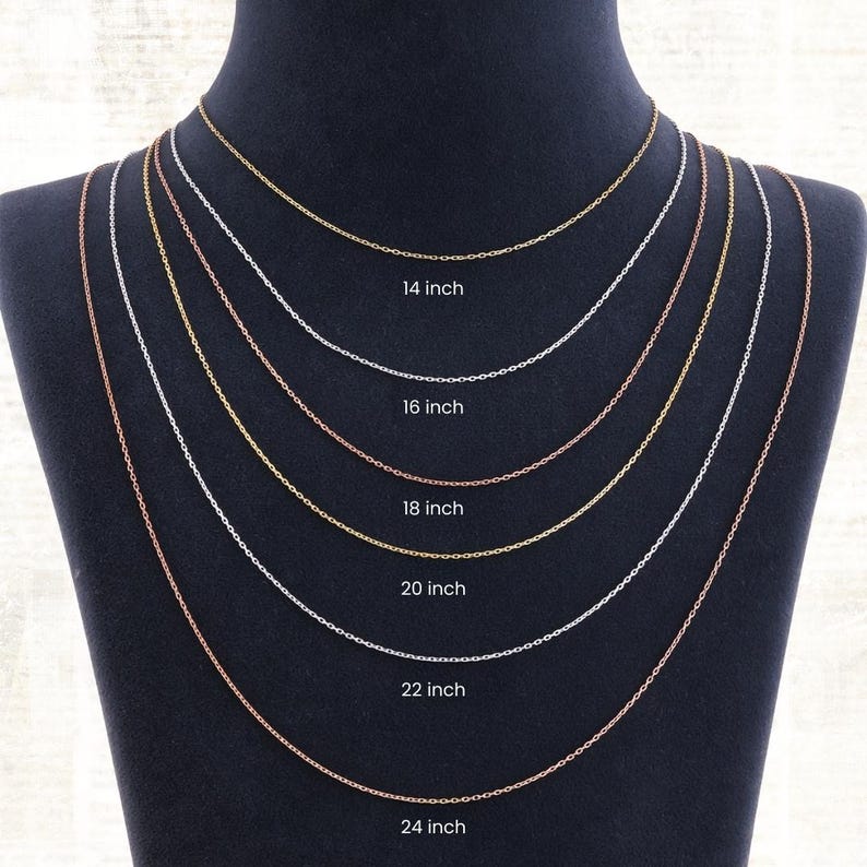 May include: A display of six delicate chain necklaces in varying lengths from 14 to 24 inches. The chains are in gold, silver, and rose gold tones, each labeled with its length. The necklaces are draped on a black mannequin.