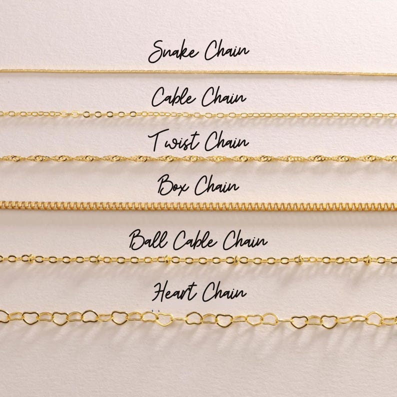 May include: A selection of gold-colored chain necklaces, including snake, cable, twist, box, ball cable, and heart chains. Each chain style is labeled with elegant cursive text. The chains are displayed against a neutral background.