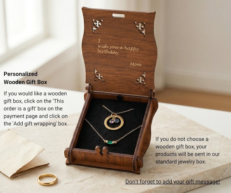 Puede incluir: Caja de regalo de joyer&iacute;a de madera abierta, que revela dos collares de oro con piedras preciosas. La caja est&aacute; grabada con "I wish you a happy birthday" y "Mom". La caja est&aacute; sobre una superficie clara, con un anillo de oro visible.