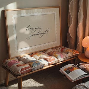 May include: A wooden bench with a patterned cushion and a framed print. The print has the words "love you, goodnight" in cursive. An open book and a small lamp are also visible.