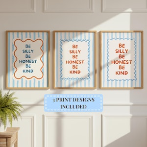 May include: Three framed wall art prints featuring a light blue and white vertical striped background. Each print displays the text BE SILLY BE HONEST BE KIND inside a scalloped border. The text and borders alternate between blue and orange colours.