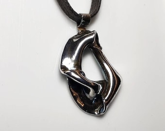 Può includere: Una collana con un ciondolo astratto in argento e un cordoncino marrone. Il ciondolo è una forma di cerchio aperto e attorcigliato.