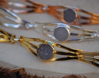 May include: Three bracelets in gold, silver and rose gold, each featuring a round, grey, sparkly stone in the centre.