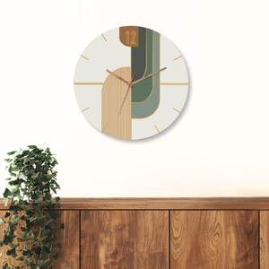 May include: A white clock with gold and green geometric shapes and the number 12 on the face.