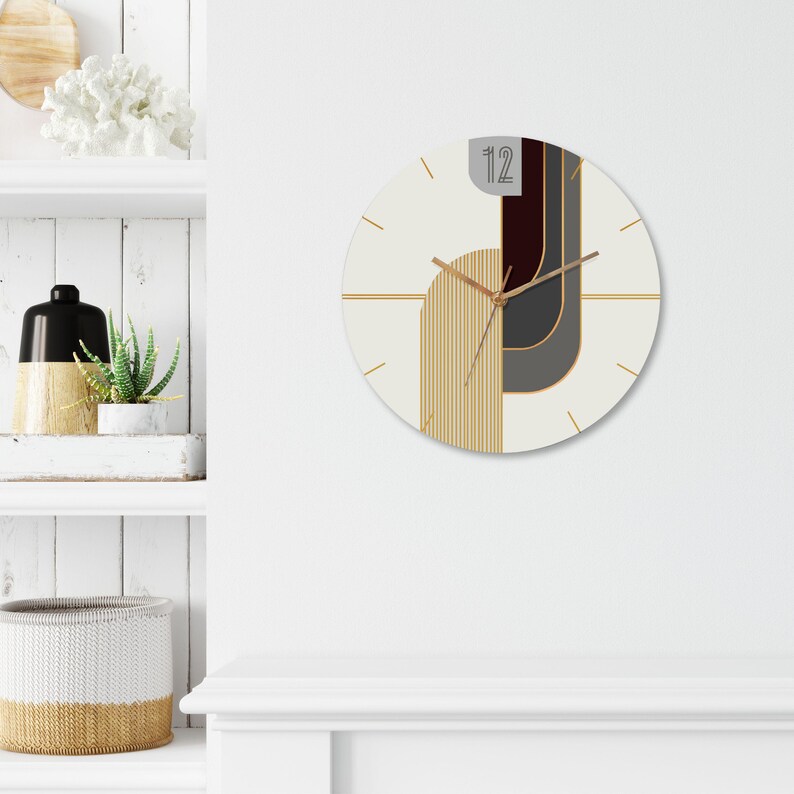 May include: A white and gold geometric wall clock with black and brown accents. The clock face features a design of overlapping shapes and lines. The clock hands are gold and the numbers are black.