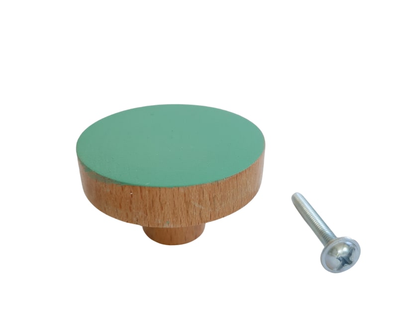 K&ouml;nnte beinhalten: Ein gr&uuml;ner und h&ouml;lzerner Knopf mit einer Schraube. Der Knopf ist rund und hat eine flache Oberseite. Die Schraube ist silberfarben.