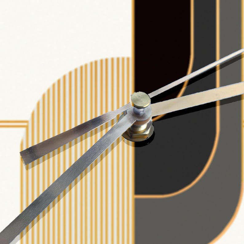 May include: Close-up of silver clock hands with a gold-colored center piece. The hands are against a background of black and gold stripes.