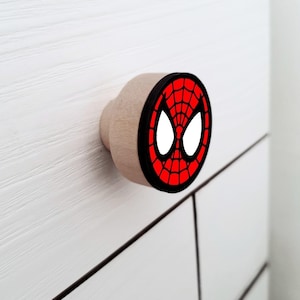 以下が含まれることがあります： スパイダーマンの顔のデザインが施された赤と黒のウッド製の引き出しノブです。