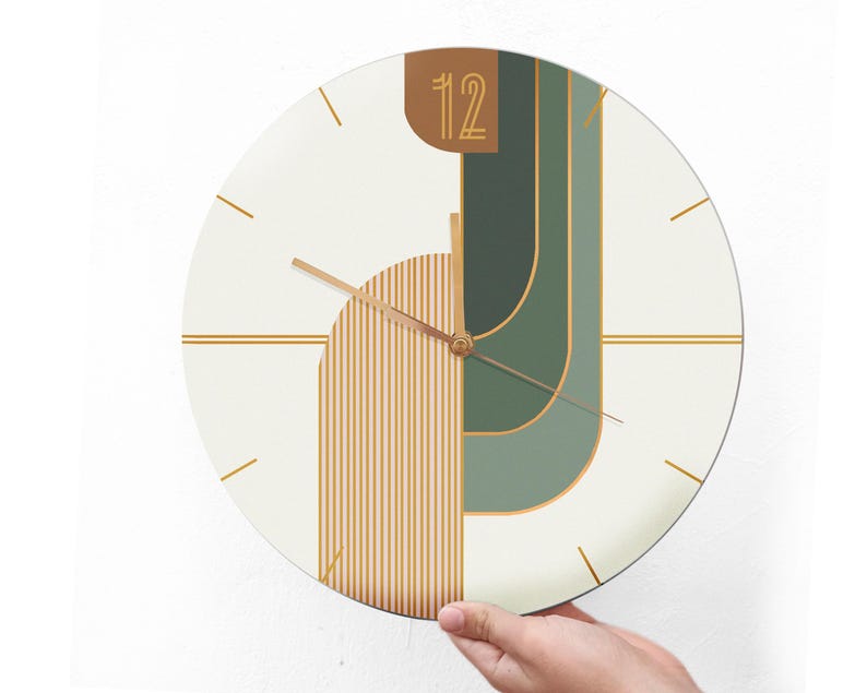 May include: A white circular clock with gold and green geometric shapes and gold hands. The clock face has the number 12 in gold.