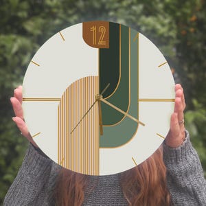 May include: A white round clock with gold and green geometric shapes and gold hands. The clock face has the number "12" in a gold rectangle.