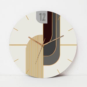 May include: White round clock with gold hands and a geometric design featuring black, gray, and gold stripes. The clock face has the number "12" printed on it.