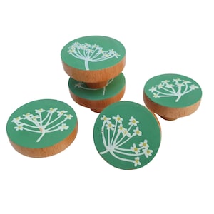 May include: Four wooden knobs with a green background and white flower designs. The knobs are stacked on top of each other.