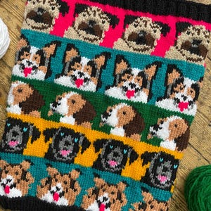 May include: A knitted blanket with a repeating pattern of different dog breeds. The blanket showcases pugs and other dogs in brown, black, and white, set against pink, teal, green, and yellow backgrounds. The edges are black.