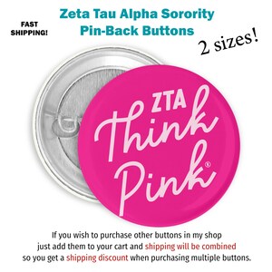 May include: A pink button with white text that reads "ZTA Think Pink". The button is a pin-back style and is available in two sizes.